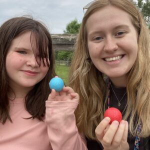 Child and young woman holding red and blue balls.