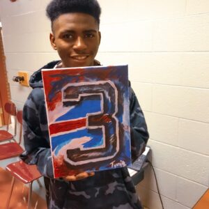A young teen holding a Buffalo Bills painting.